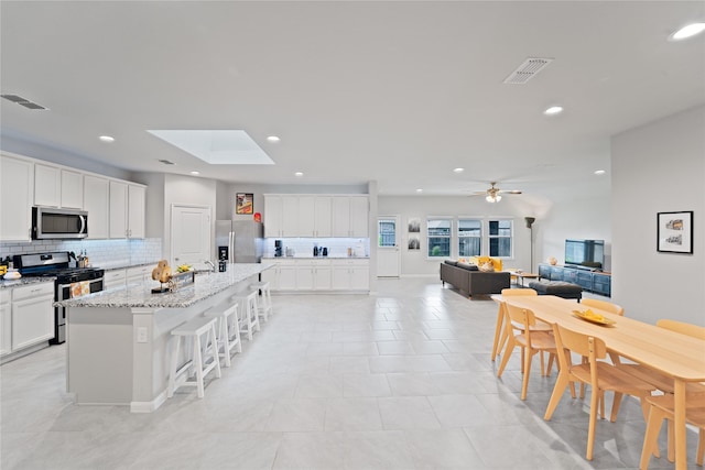 1318 Bellingham Park Dr, Missouri City, TX 77459 - kitchen featuring stainless steel appliances, tasteful backsplash, white cabinetry, a breakfast bar, and recessed lighting