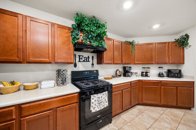 5327 Castle Discordia St, Katy, TX 77493 - kitchen featuring black gas range oven, light countertops, under cabinet range hood, brown cabinetry, and light tile patterned floors