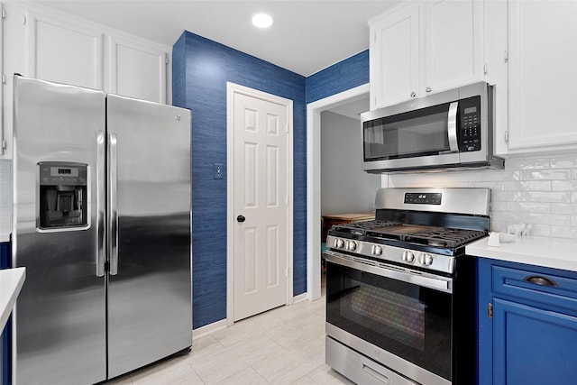 1402 Osborne Dr, Friendswood, TX 77546 - kitchen featuring stainless steel appliances, blue cabinetry, light countertops, white cabinetry, and backsplash