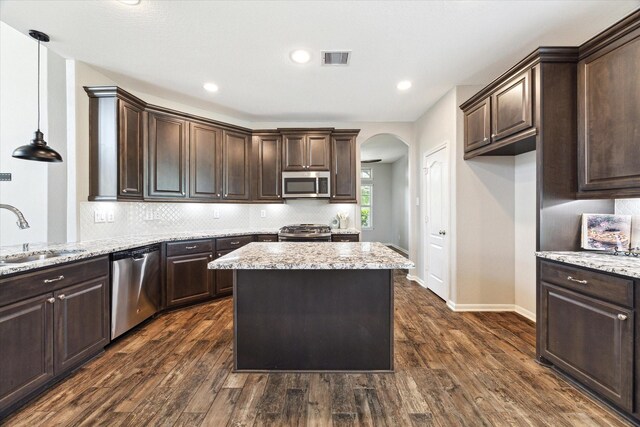 19426 Blueberry Cedar Dr, Cypress, TX 77433 - kitchen featuring stainless steel appliances, a sink, arched walkways, dark brown cabinetry, and recessed lighting
