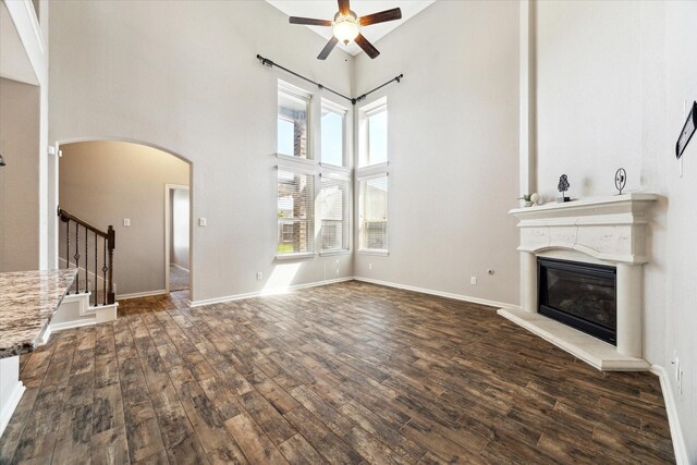 19426 Blueberry Cedar Dr, Cypress, TX 77433 - unfurnished living room featuring ceiling fan, wood finished floors, a glass covered fireplace, arched walkways, and a high ceiling