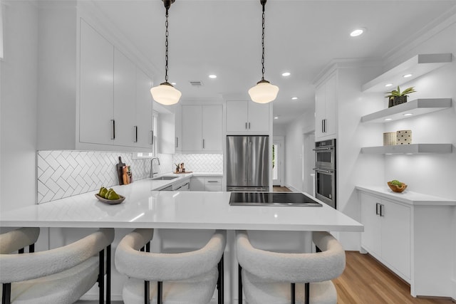 904 Willard St, Houston, TX 77006 - kitchen featuring appliances with stainless steel finishes, a peninsula, a sink, decorative backsplash, and light countertops