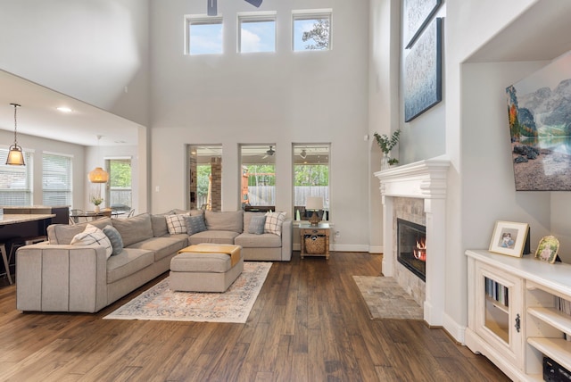 2678 Granite River Ln, Conroe, TX 77385 - living room featuring ceiling fan, a fireplace, dark wood-style flooring, a high ceiling, and baseboards