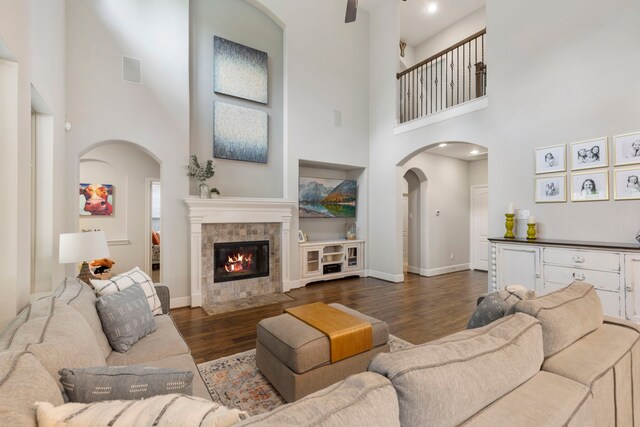 2678 Granite River Ln, Conroe, TX 77385 - living area featuring arched walkways, dark wood finished floors, a high ceiling, a fireplace, and baseboards