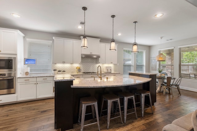 2678 Granite River Ln, Conroe, TX 77385 - kitchen featuring stainless steel appliances, a sink, a center island with sink, under cabinet range hood, and backsplash