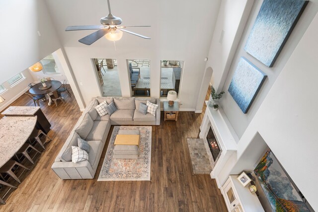 2678 Granite River Ln, Conroe, TX 77385 - living area featuring a towering ceiling, wood finished floors, a ceiling fan, baseboards, and a brick fireplace
