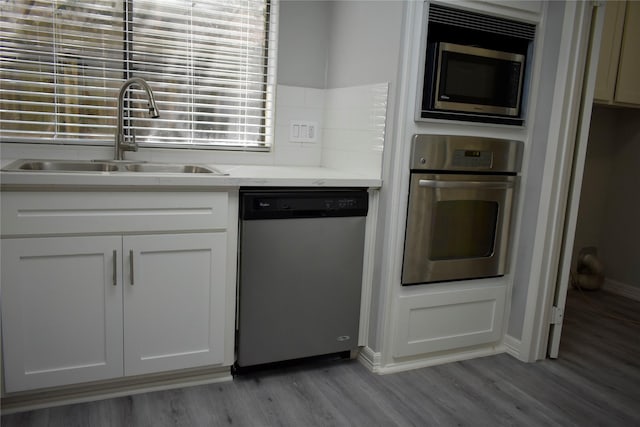 10011 Sageorchard Ln, Houston, TX 77089 - kitchen with appliances with stainless steel finishes, a sink, light wood finished floors, and baseboards
