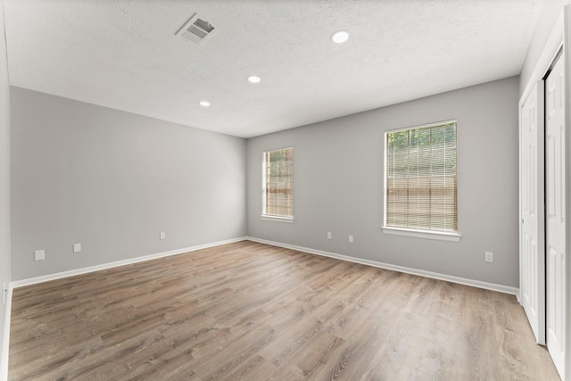 235 E Rainbow Ridge Cir, The Woodlands, TX 77381 - spare room featuring a textured ceiling, light wood-style flooring, and recessed lighting