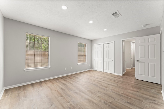235 E Rainbow Ridge Cir, The Woodlands, TX 77381 - unfurnished bedroom with recessed lighting, a textured ceiling, light wood finished floors, and a closet