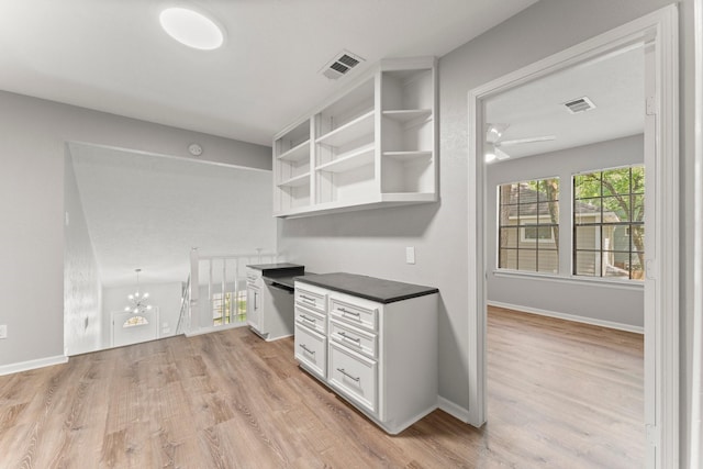 235 E Rainbow Ridge Cir, The Woodlands, TX 77381 - kitchen featuring light wood finished floors, dark countertops, white cabinets, open shelves, and a chandelier