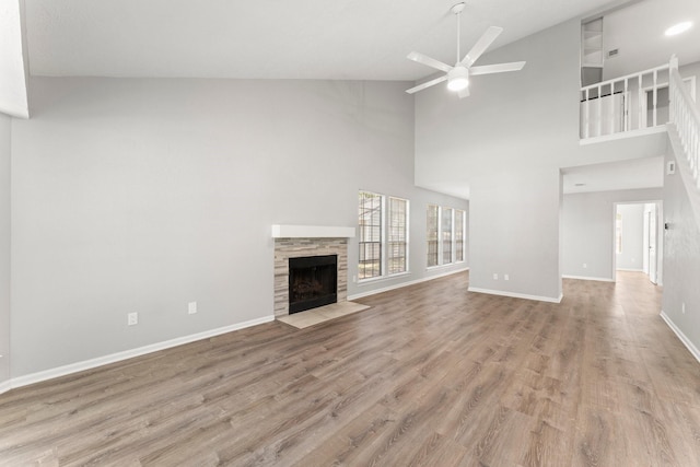 235 E Rainbow Ridge Cir, The Woodlands, TX 77381 - unfurnished living room featuring a ceiling fan, a fireplace, wood finished floors, and high vaulted ceiling