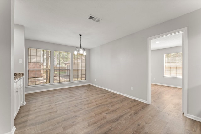 235 E Rainbow Ridge Cir, The Woodlands, TX 77381 - unfurnished dining area with a chandelier, healthy amount of natural light, and light wood finished floors