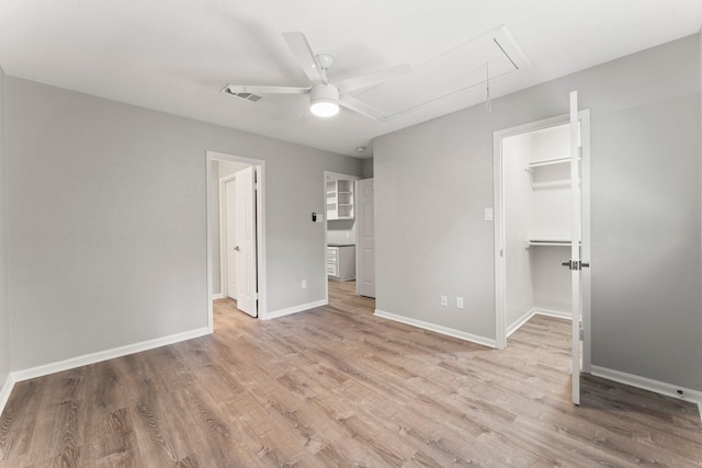 235 E Rainbow Ridge Cir, The Woodlands, TX 77381 - unfurnished bedroom with attic access, a walk in closet, light wood-type flooring, and ceiling fan