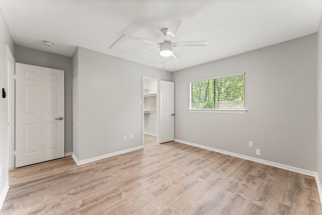 235 E Rainbow Ridge Cir, The Woodlands, TX 77381 - unfurnished bedroom with light wood-type flooring, a ceiling fan, a spacious closet, and a closet
