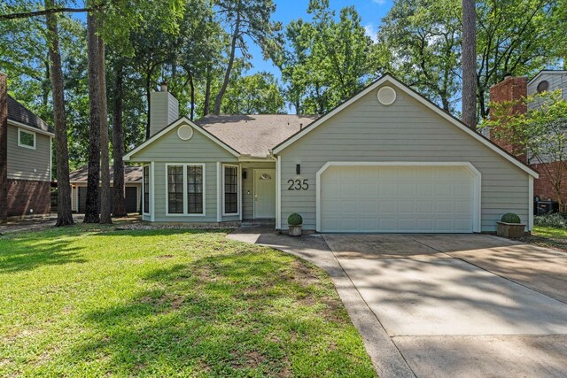 235 E Rainbow Ridge Cir, The Woodlands, TX 77381 - view of front of house with driveway, a chimney, a garage, and a front lawn