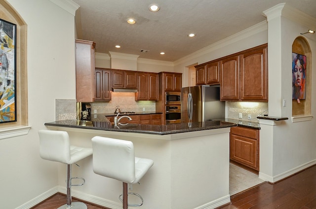 2918 Royal Oaks Grn, Houston, TX 77082 - kitchen featuring appliances with stainless steel finishes, a peninsula, recessed lighting, backsplash, and light wood finished floors