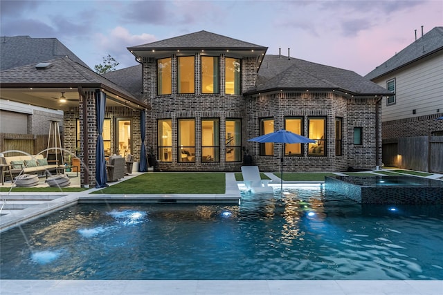 271 Bronze View Dr, Montgomery, TX 77316 - back of property at dusk with brick siding, a pool with connected hot tub, a patio area, and a shingled roof