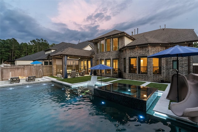 271 Bronze View Dr, Montgomery, TX 77316 - back of property at dusk featuring brick siding, area for grilling, a patio, and a shingled roof