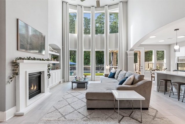 271 Bronze View Dr, Montgomery, TX 77316 - living area featuring a high ceiling, arched walkways, a glass covered fireplace, and built in shelves