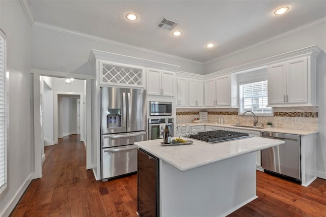 615 Allston St, Houston, TX 77007 - kitchen featuring appliances with stainless steel finishes, a sink, white cabinetry, crown molding, and backsplash