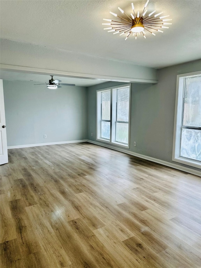 312 Bridal Wreath Ave, Orange, TX 77630 - spare room featuring a chandelier, wood finished floors, baseboards, ceiling fan, and a textured ceiling