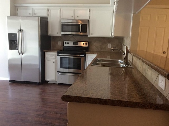 5 Lazybrook St, Angleton, TX 77515 - kitchen with appliances with stainless steel finishes, a sink, dark wood-style flooring, tasteful backsplash, and white cabinets