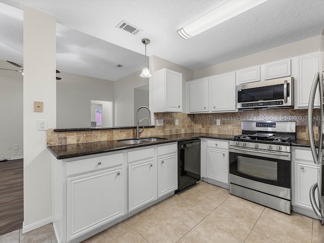 27097 Crown Chase Dr, Kingwood, TX 77339 - kitchen with stainless steel appliances, a sink, white cabinets, backsplash, and hanging light fixtures