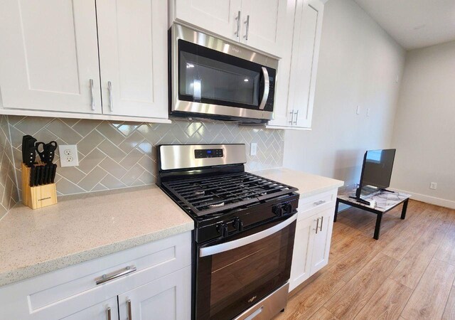 615 Northew St Unit J, Houston, TX 77091 - kitchen with appliances with stainless steel finishes, light wood finished floors, white cabinetry, and decorative backsplash