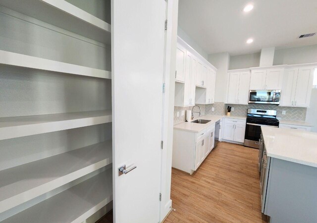 615 Northew St Unit J, Houston, TX 77091 - kitchen with appliances with stainless steel finishes, white cabinets, decorative backsplash, recessed lighting, and a sink