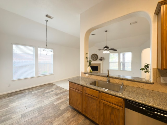 4906 Arbor Falls Ln, Houston, TX 77084 - kitchen featuring stainless steel dishwasher, a sink, arched walkways, lofted ceiling, and a fireplace with raised hearth