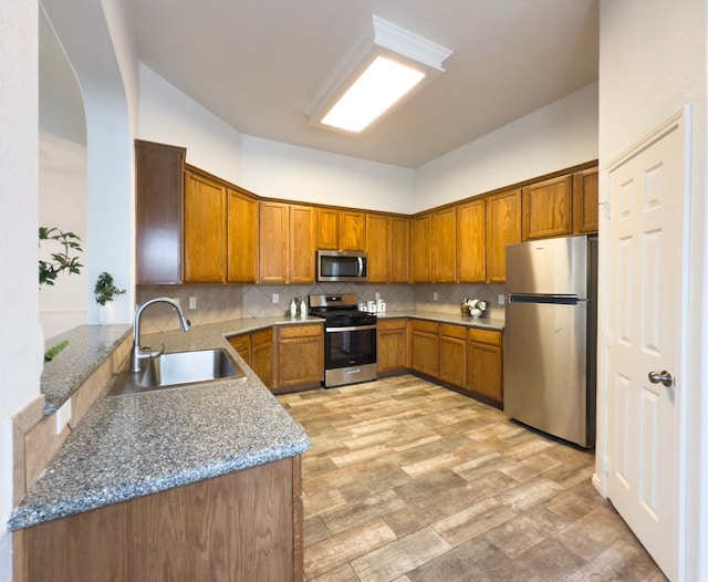 4906 Arbor Falls Ln, Houston, TX 77084 - kitchen with appliances with stainless steel finishes, a sink, brown cabinets, and stone countertops