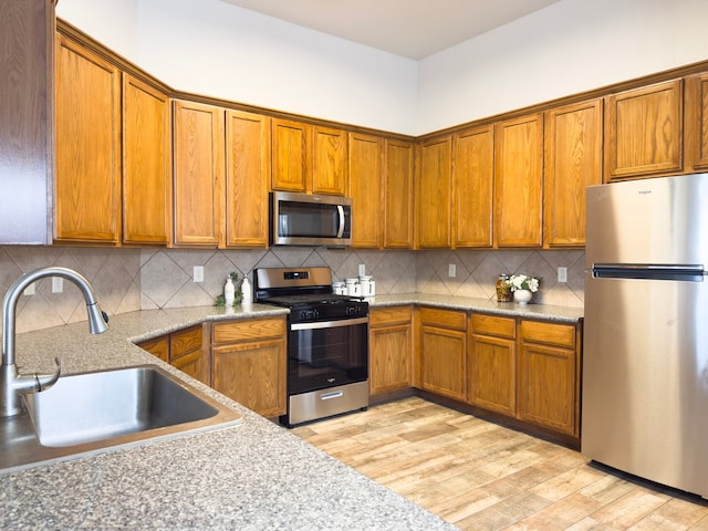 4906 Arbor Falls Ln, Houston, TX 77084 - kitchen with appliances with stainless steel finishes, a sink, brown cabinetry, and light wood-type flooring