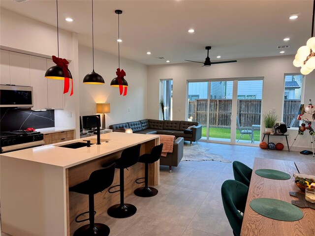 113 E 32nd St Unit A, Houston, TX 77018 - kitchen featuring stainless steel microwave, range with gas stovetop, light countertops, white cabinets, and recessed lighting