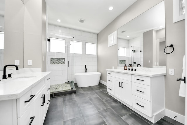 1805 Blodgett St, Houston, TX 77004 - full bathroom with a shower stall, two vanities, a freestanding bath, recessed lighting, and baseboards