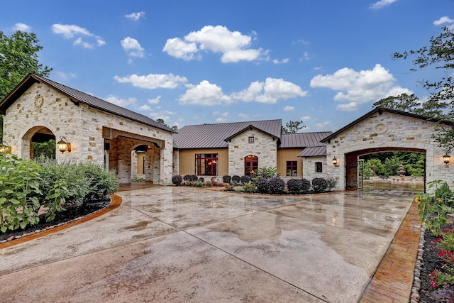 10002 Oxted Ln, Spring, TX 77379 - french country inspired facade with a standing seam roof, stone siding, metal roof, and concrete driveway