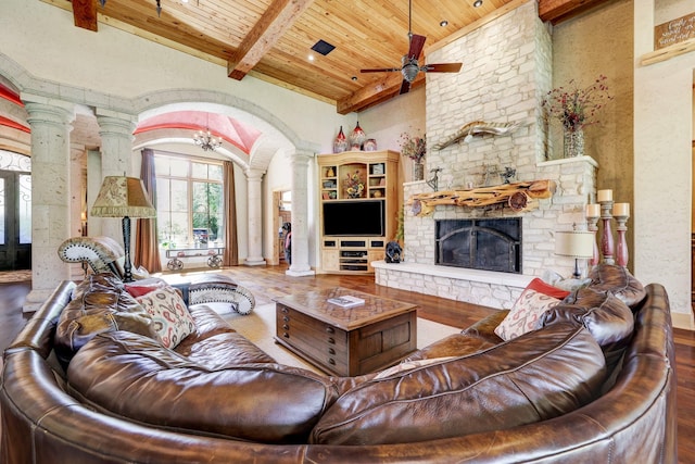 10002 Oxted Ln, Spring, TX 77379 - living room with decorative columns, wood ceiling with exposed beams, wood finished floors, a stone fireplace, and ceiling fan