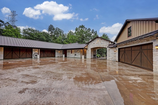 10002 Oxted Ln, Spring, TX 77379 - view of front of home featuring board and batten siding, stone siding, concrete driveway, a garage, and metal roof
