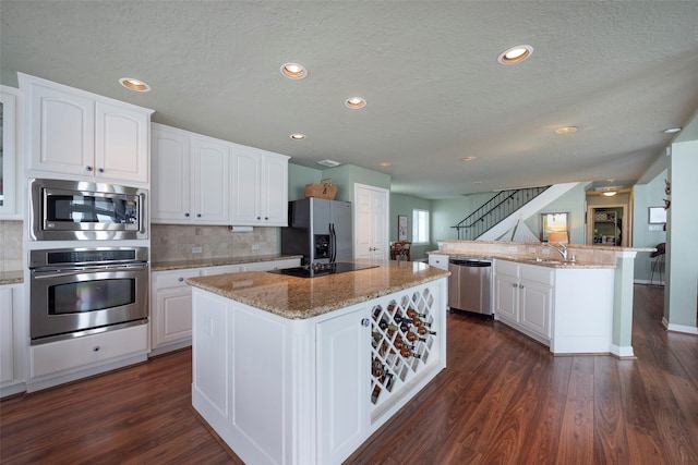 131 Isles End Rd, Tiki Island, TX 77554 - kitchen with appliances with stainless steel finishes, a kitchen island, a textured ceiling, white cabinets, and decorative backsplash