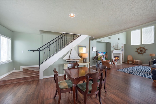 131 Isles End Rd, Tiki Island, TX 77554 - dining room with a textured ceiling, stairs, baseboards, wood finished floors, and a warm lit fireplace