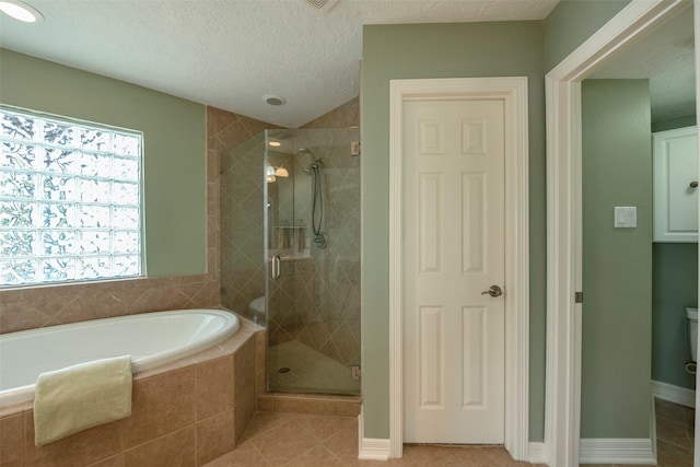 131 Isles End Rd, Tiki Island, TX 77554 - bathroom featuring a garden tub, a stall shower, tile patterned floors, a textured ceiling, and baseboards