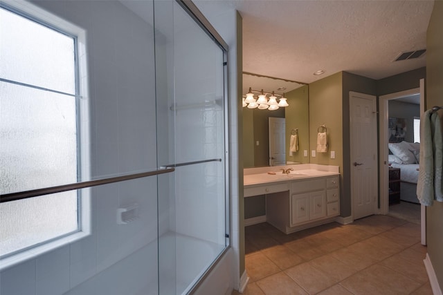 131 Isles End Rd, Tiki Island, TX 77554 - ensuite bathroom featuring vanity, plenty of natural light, tile patterned flooring, bath / shower combo with glass door, and a textured ceiling
