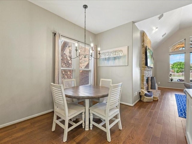 17806 Creek Bluff Ln, Cypress, TX 77433 - dining space with wood finished floors, a chandelier, baseboards, lofted ceiling, and a stone fireplace