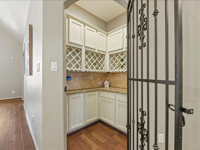 17806 Creek Bluff Ln, Cypress, TX 77433 - indoor dry bar with dark wood-style flooring, arched walkways, baseboards, tasteful backsplash, and vaulted ceiling