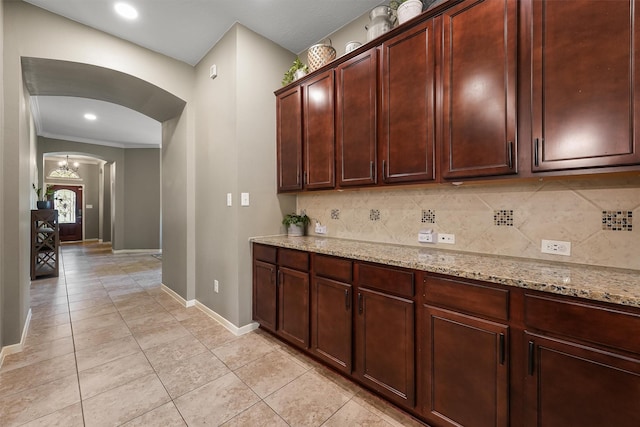 14327 Cranbrook Creek Ln, Houston, TX 77044 - kitchen with arched walkways, baseboards, tasteful backsplash, light stone counters, and light tile patterned floors