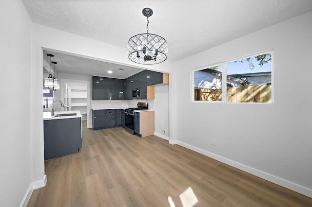 7109 Saint Augustine St, Houston, TX 77021 - kitchen featuring gas stove, a chandelier, light countertops, baseboards, and stainless steel microwave