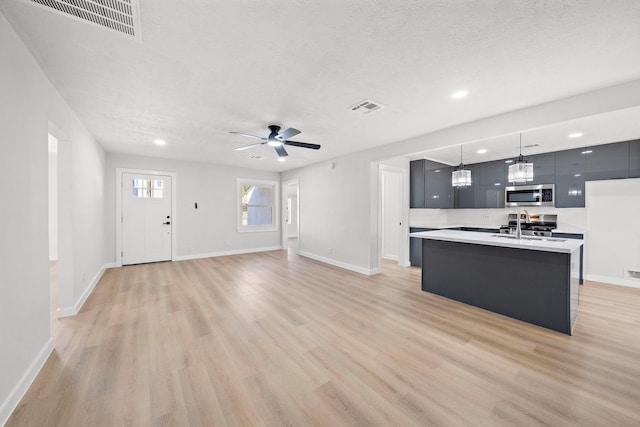 7109 Saint Augustine St, Houston, TX 77021 - kitchen featuring appliances with stainless steel finishes, modern cabinets, light countertops, a textured ceiling, and light wood-type flooring