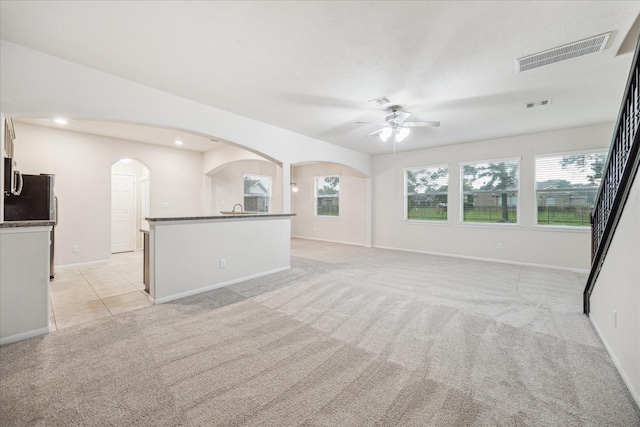 18621 Serenity Loch Dr, Spring, TX 77379 - unfurnished living room featuring arched walkways, light colored carpet, a ceiling fan, baseboards, and recessed lighting