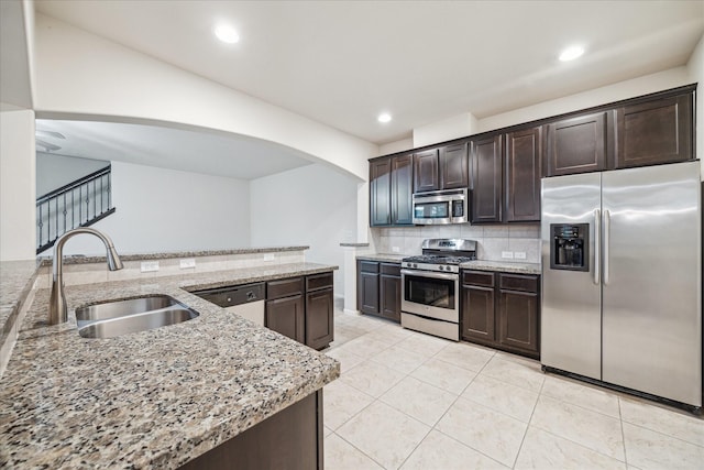 18621 Serenity Loch Dr, Spring, TX 77379 - kitchen with stainless steel appliances, a sink, dark brown cabinets, arched walkways, and recessed lighting