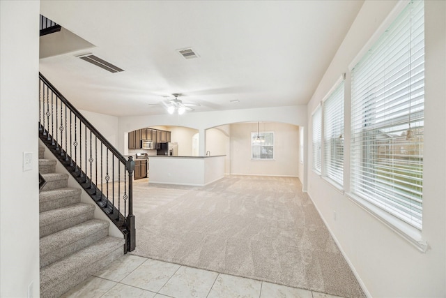 18621 Serenity Loch Dr, Spring, TX 77379 - unfurnished living room featuring arched walkways, light colored carpet, ceiling fan, baseboards, and stairway