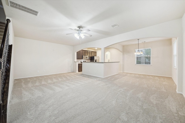 18621 Serenity Loch Dr, Spring, TX 77379 - unfurnished living room with arched walkways, ceiling fan, light carpet, and a chandelier